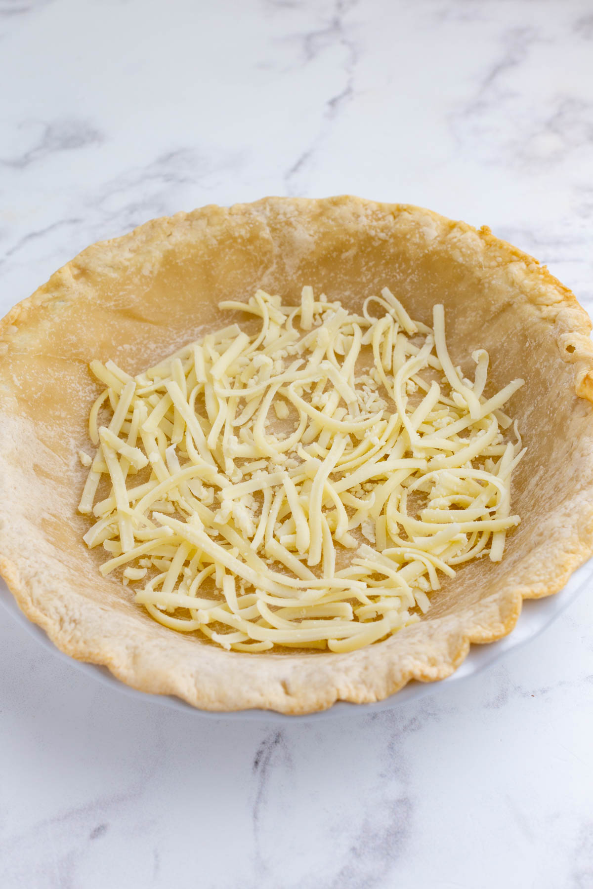 Cheese is added to a pie crust.