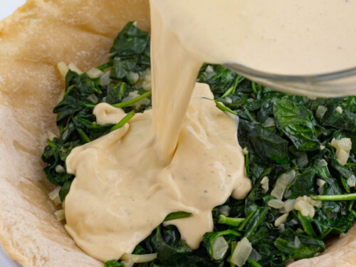 Egg mixture is poured over the spinach.