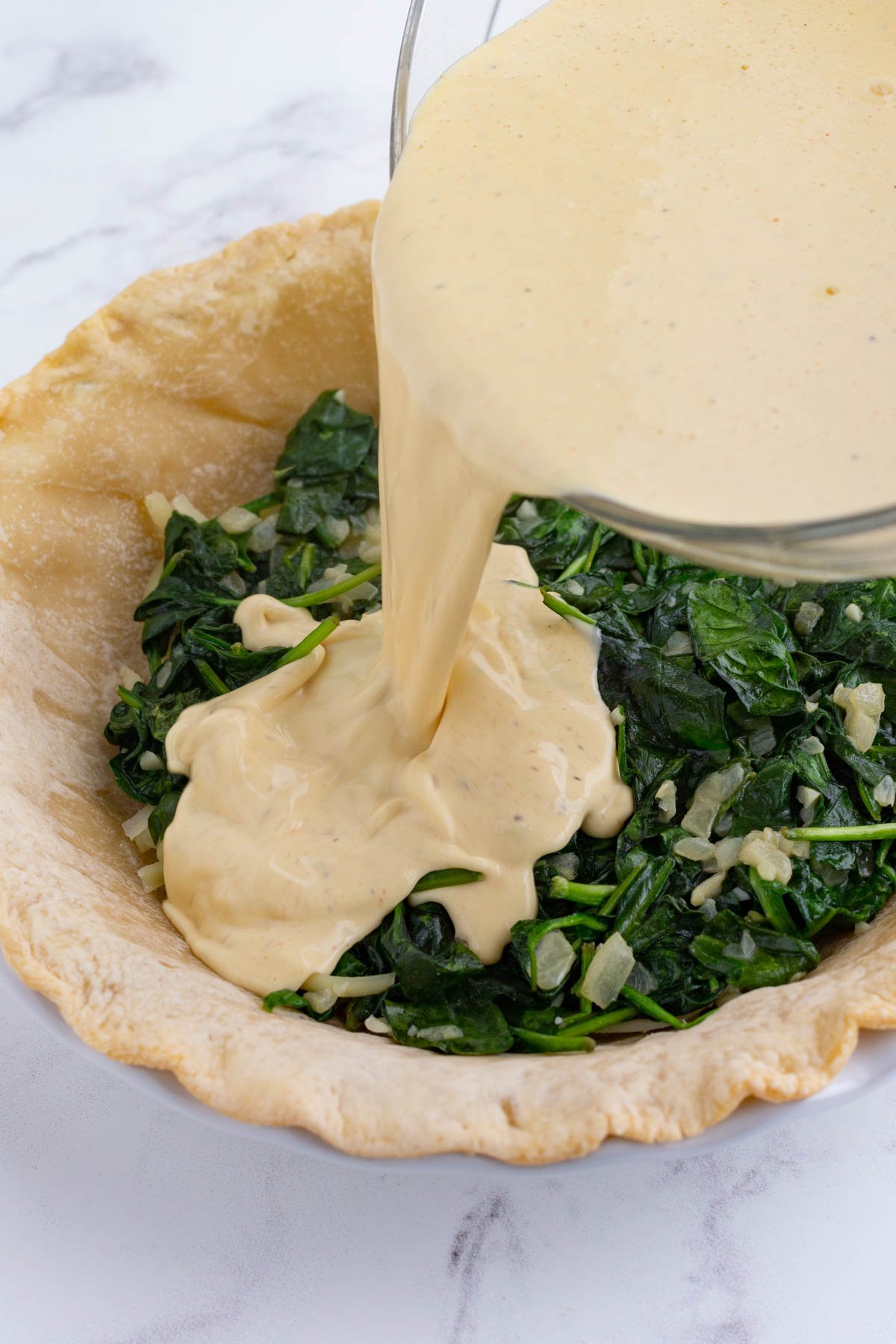 Egg mixture is poured over the spinach.