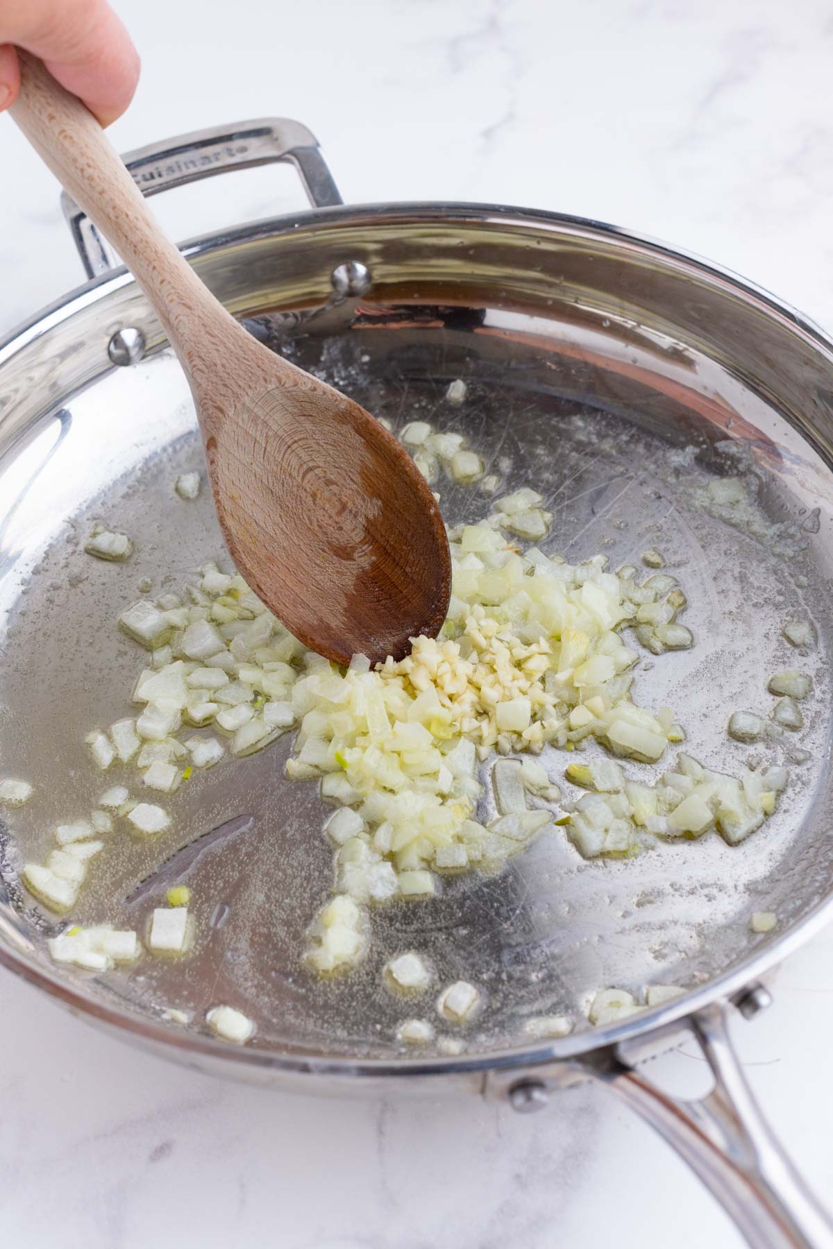 Onions and garlic are cooked in a skillet.