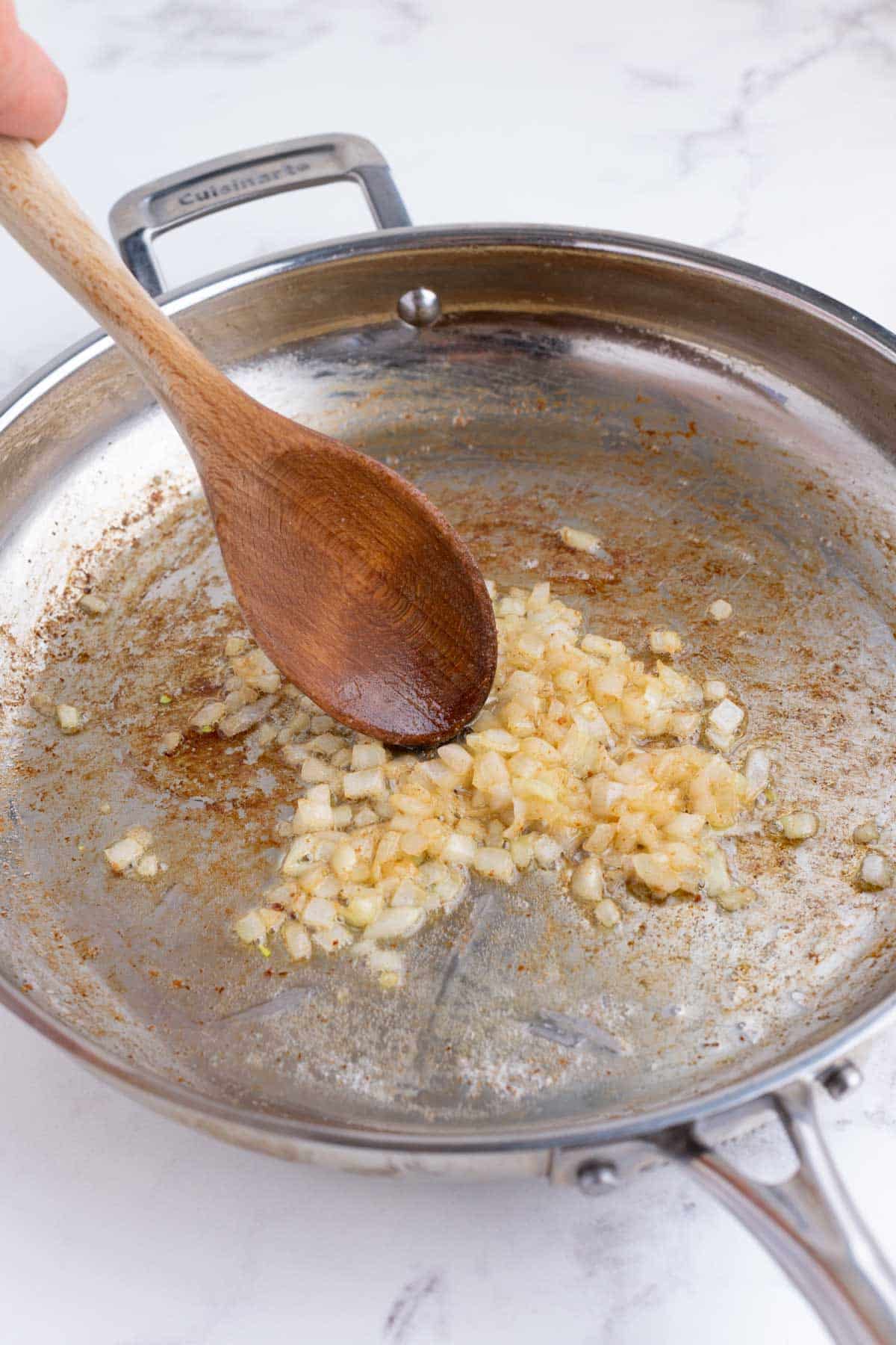 Onions are cooked in a skillet.
