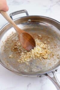 Onions and garlic are cooked in a skillet.