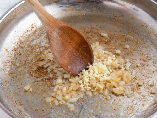 Onions and garlic are cooked in a skillet.