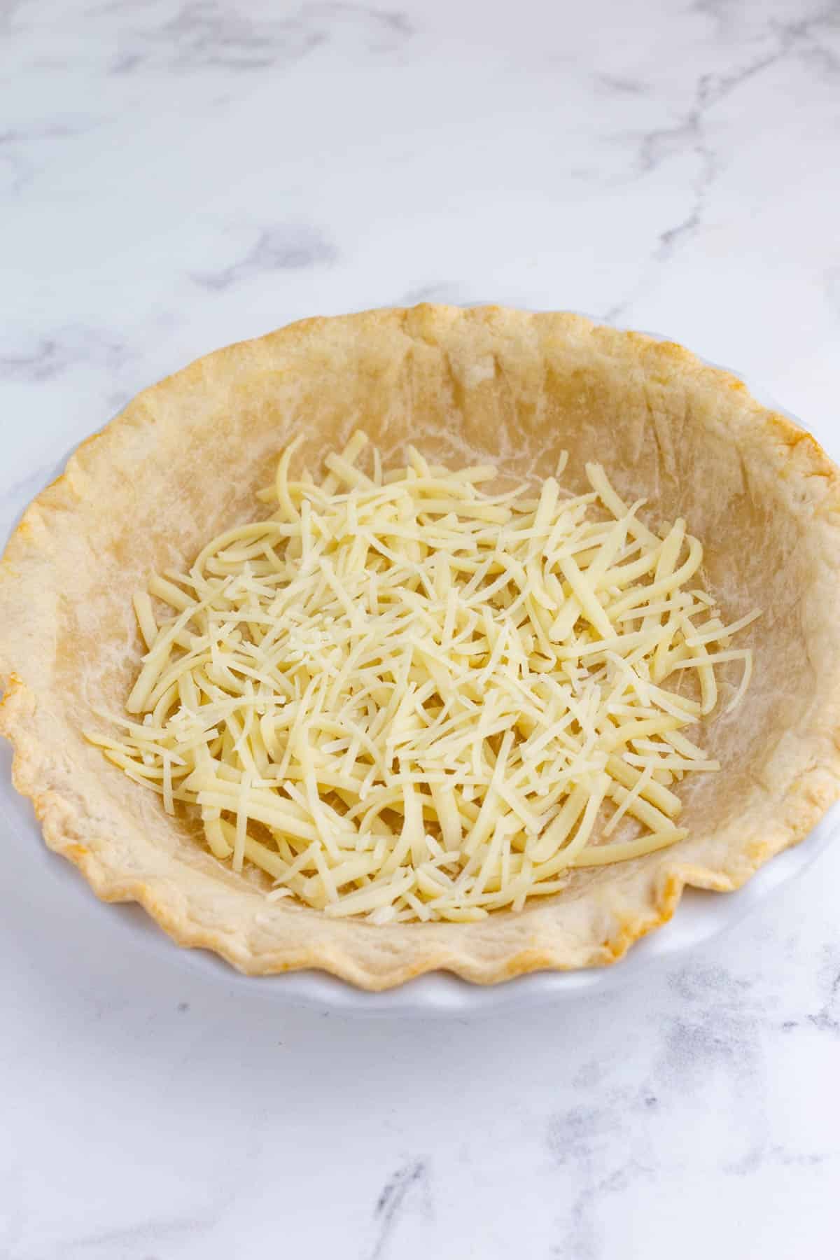 Cheese is added to a pie crust.