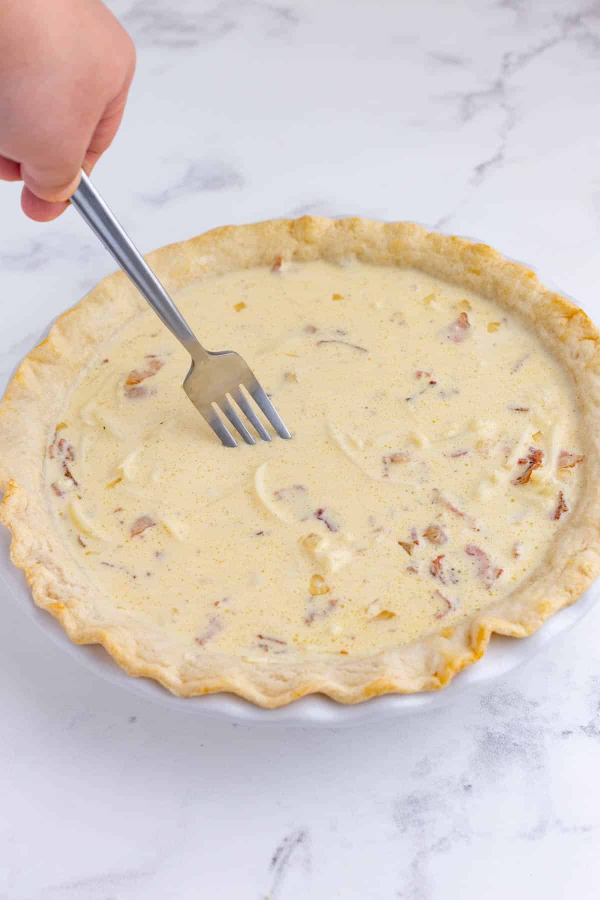 A fork stirs the fillings before baking.