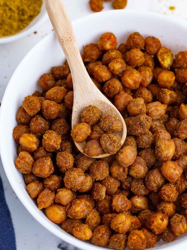 A bowl roasted chickpeas are served in a bowl with a scoop.