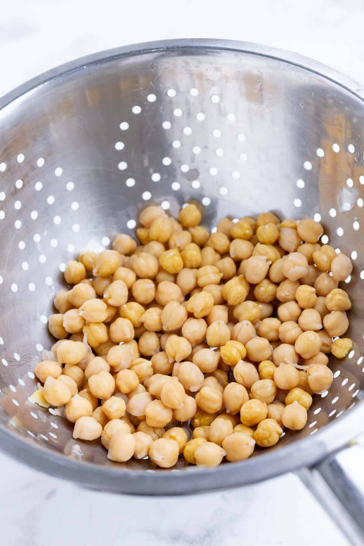 Chickpeas are drained in a colander.