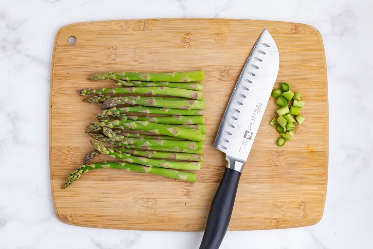 A knife slices the ends of asparagus off.