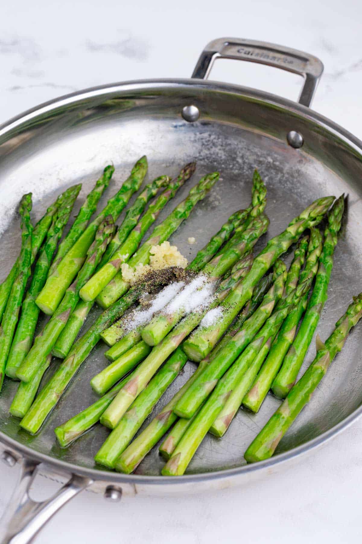 Garlic and seasonings are added to the asparagus.