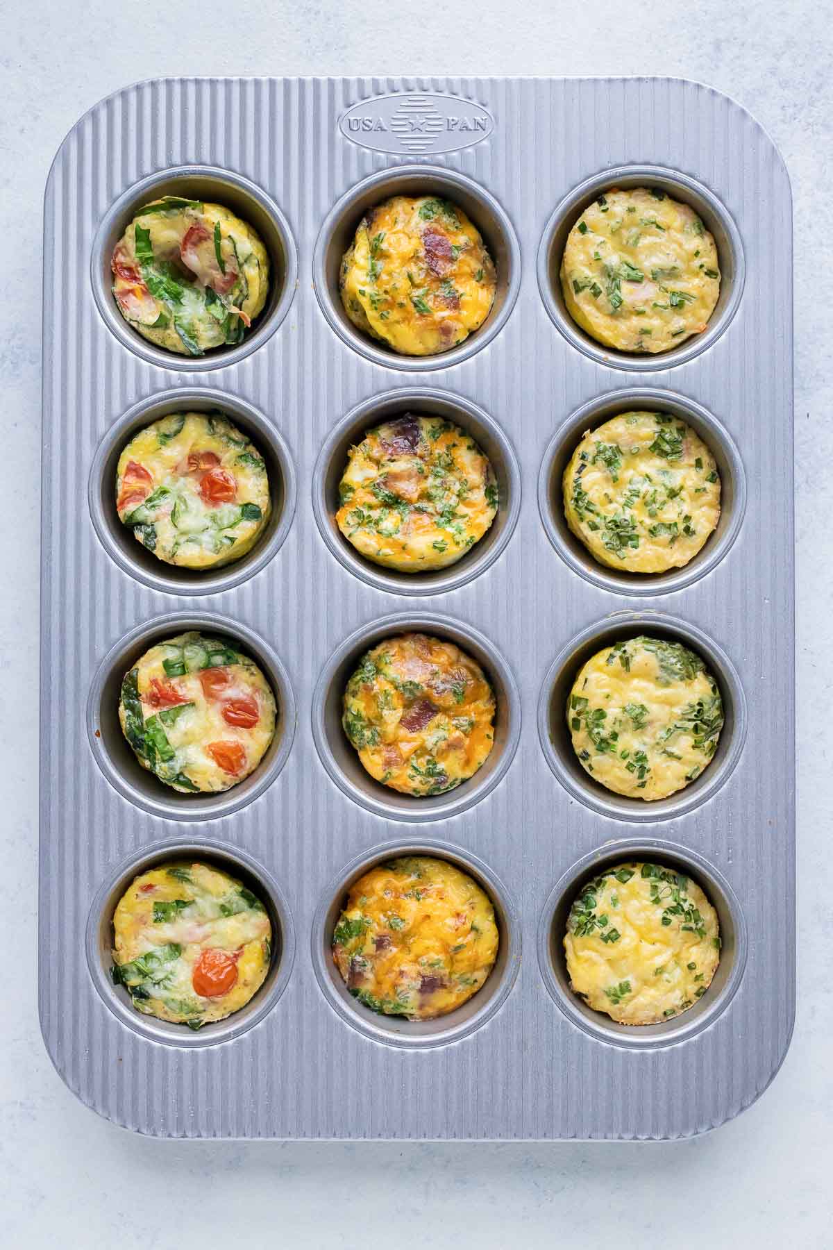 Egg muffins are cooked with different add-ins in a muffin pan in the oven.