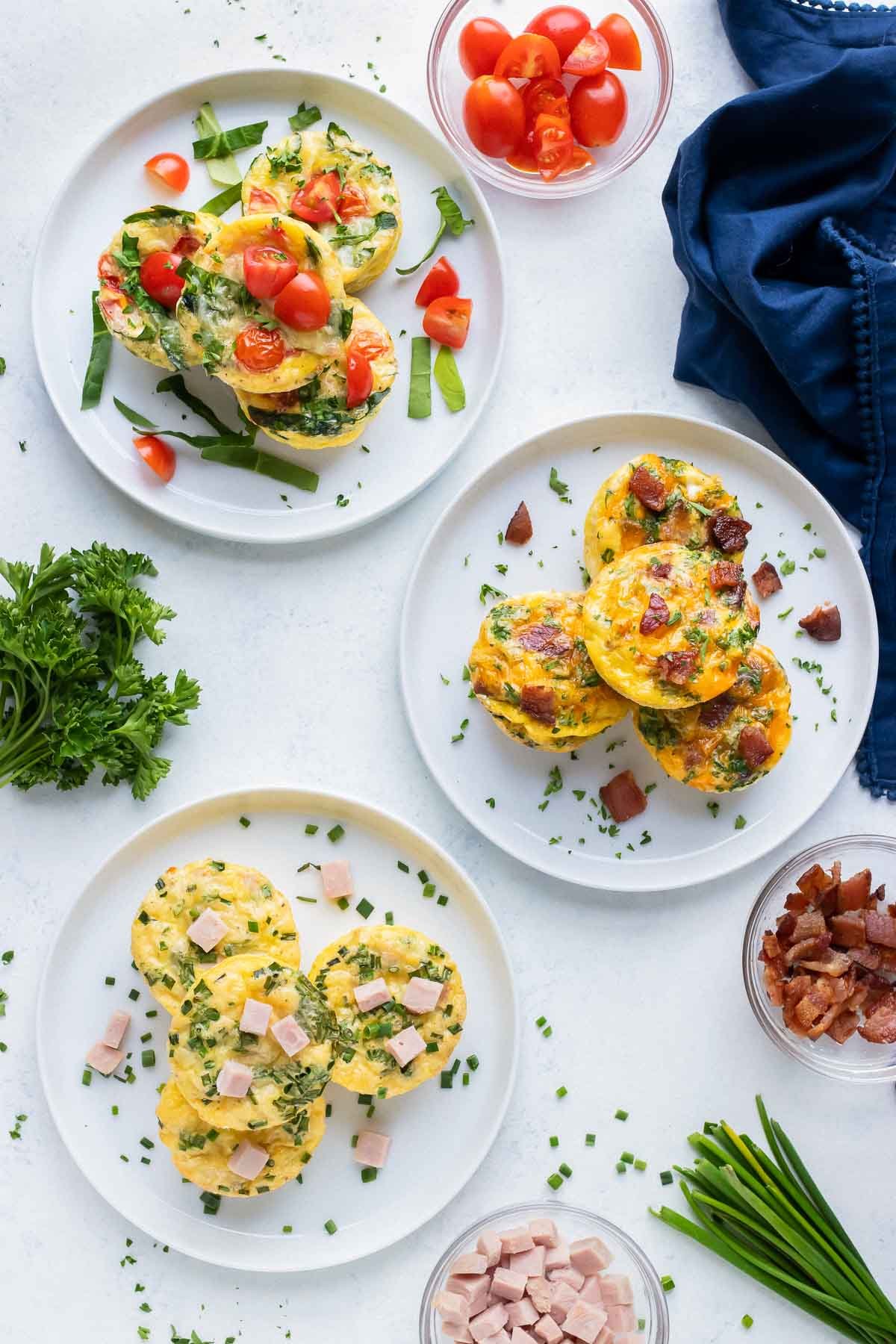 Multiple egg muffins are separated by flavor and plated for breakfast.