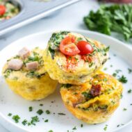 Keto egg cups are served on a plate with fresh herbs.