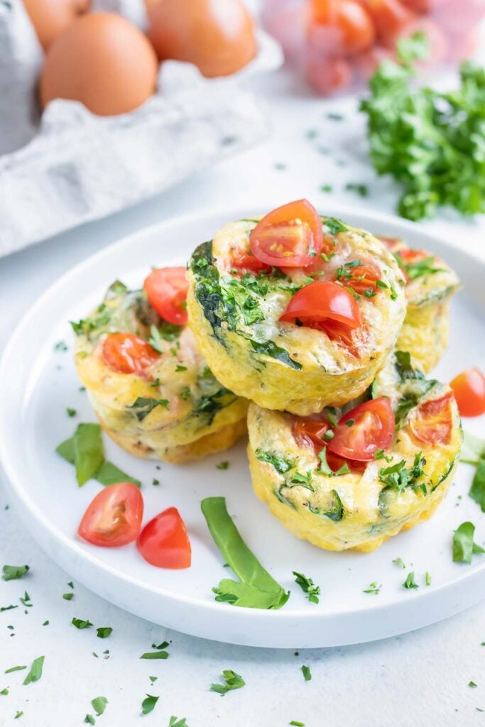 Baked spinach egg muffins with tomatoes served on a plate.