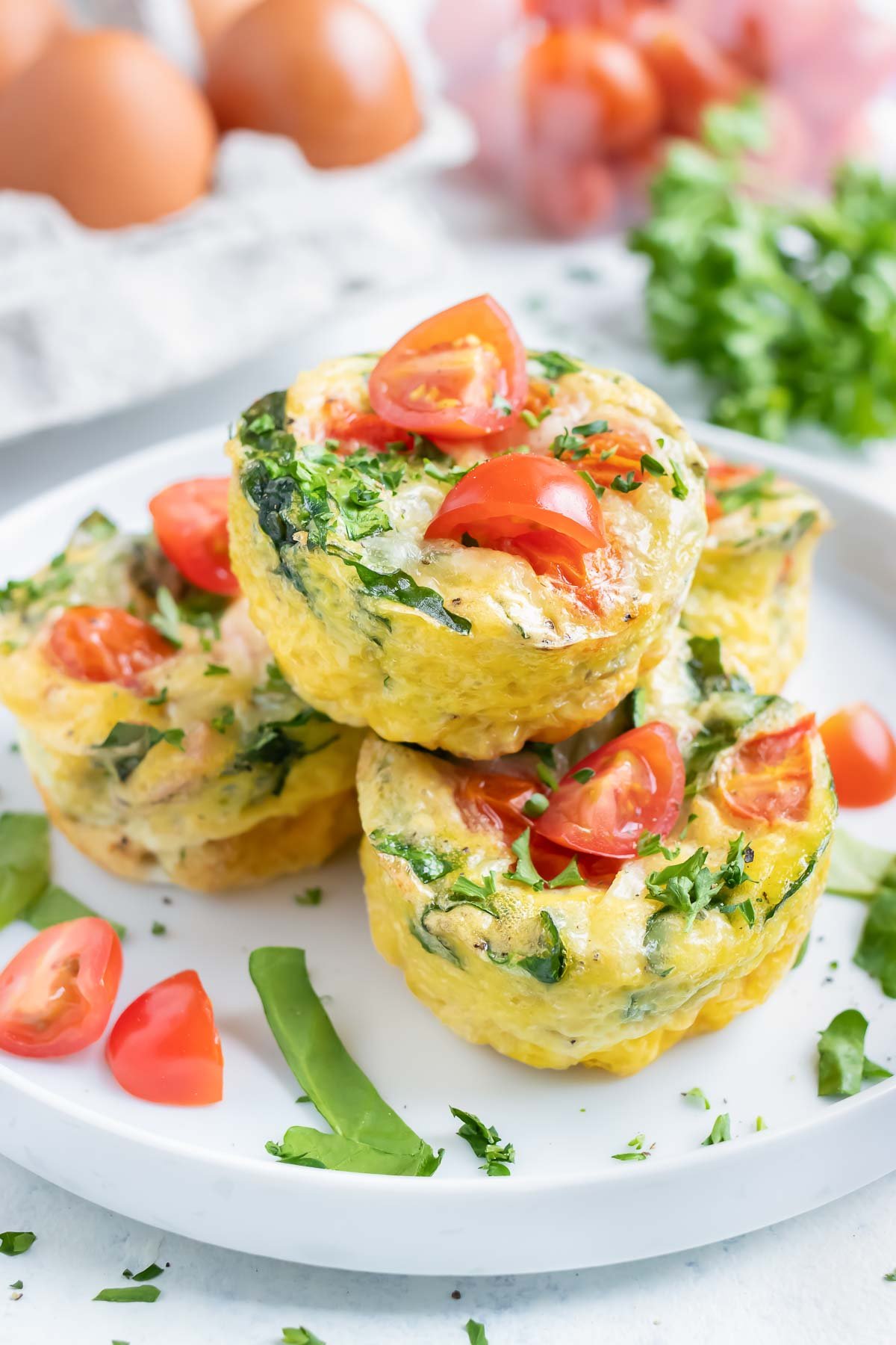 A pile of four egg muffins are served on a white plate.