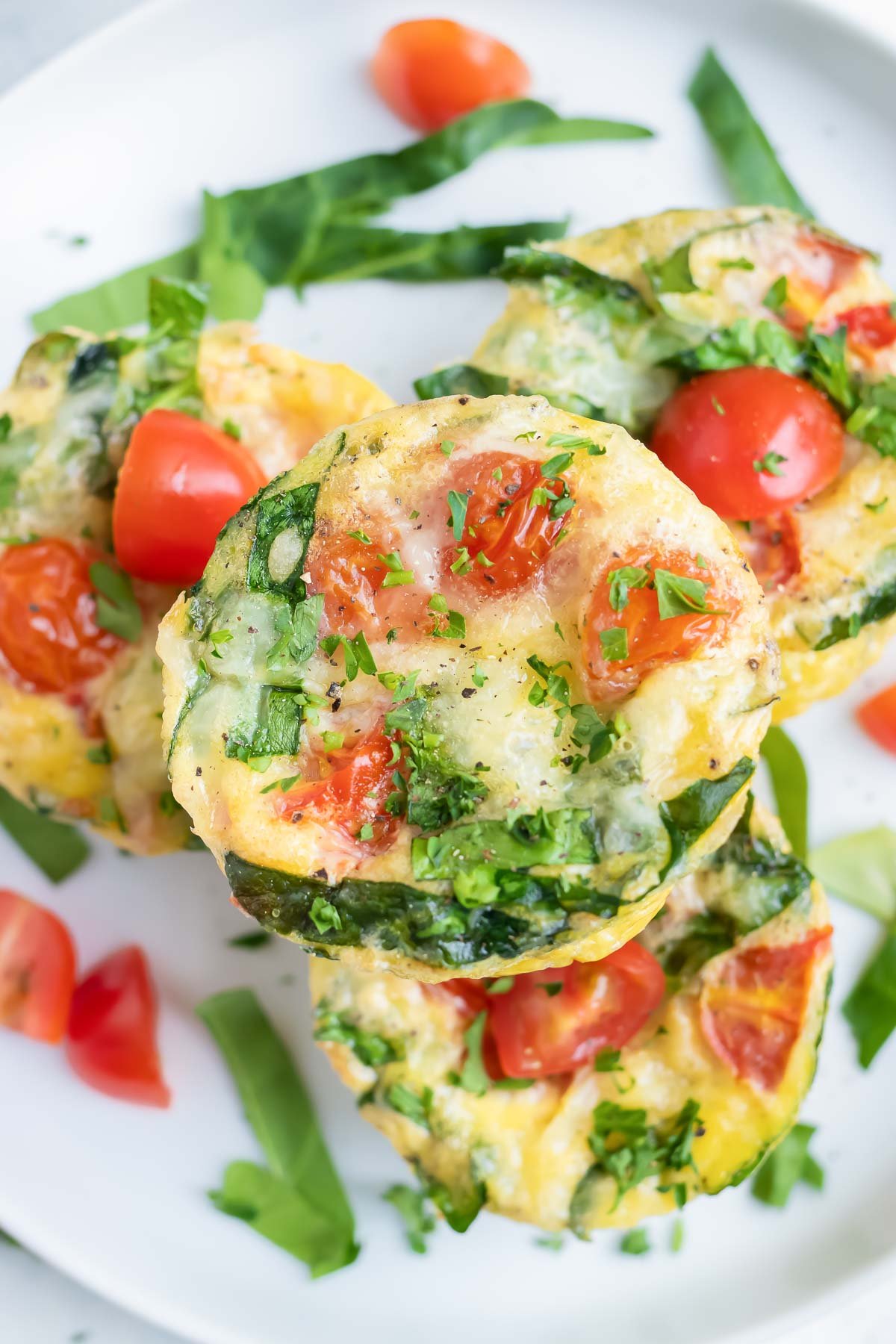 An overhead shot of spinach egg muffins with tomatoes are served for a low-carb breakfast.
