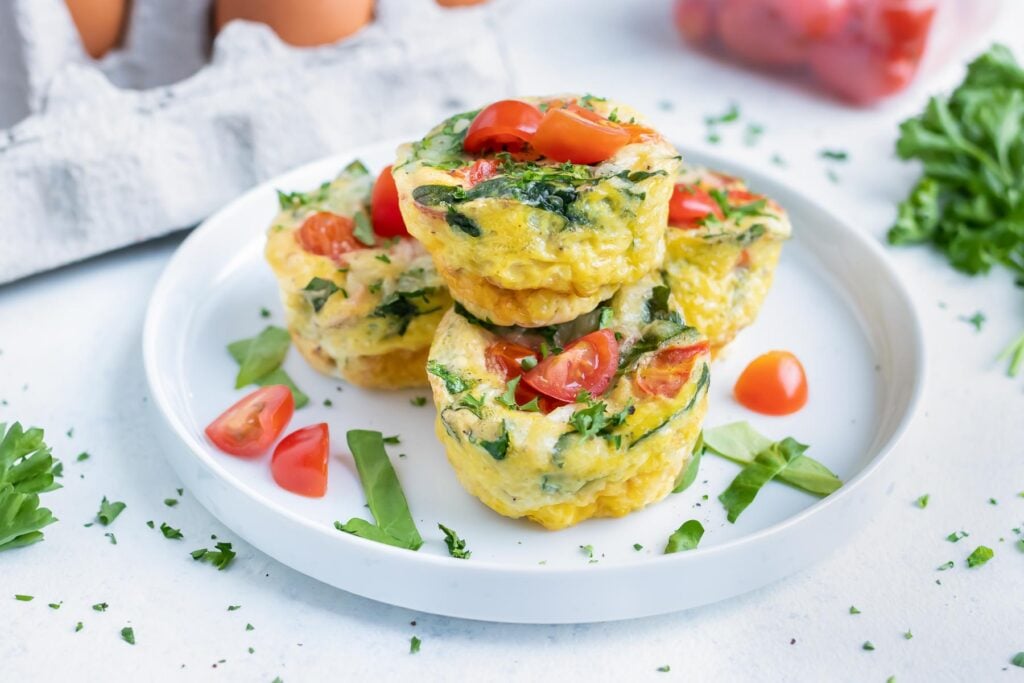 Spinach egg muffins with tomatoes served on a plate for an easy breakfast.