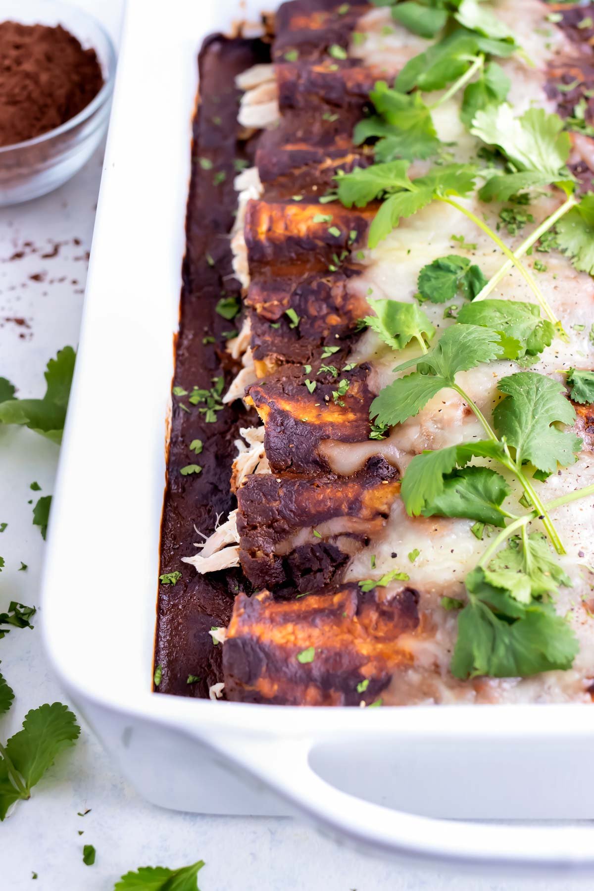 A pan of chicken enchiladas is served on the counter.