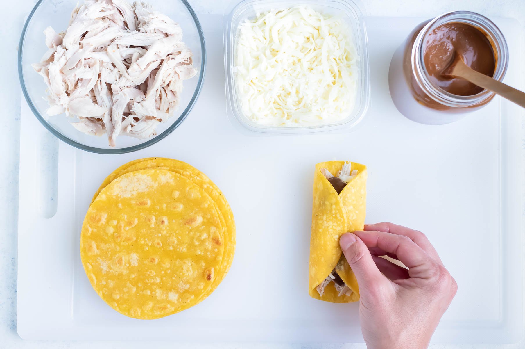 Chicken enchiladas are assembled and rolled tight.