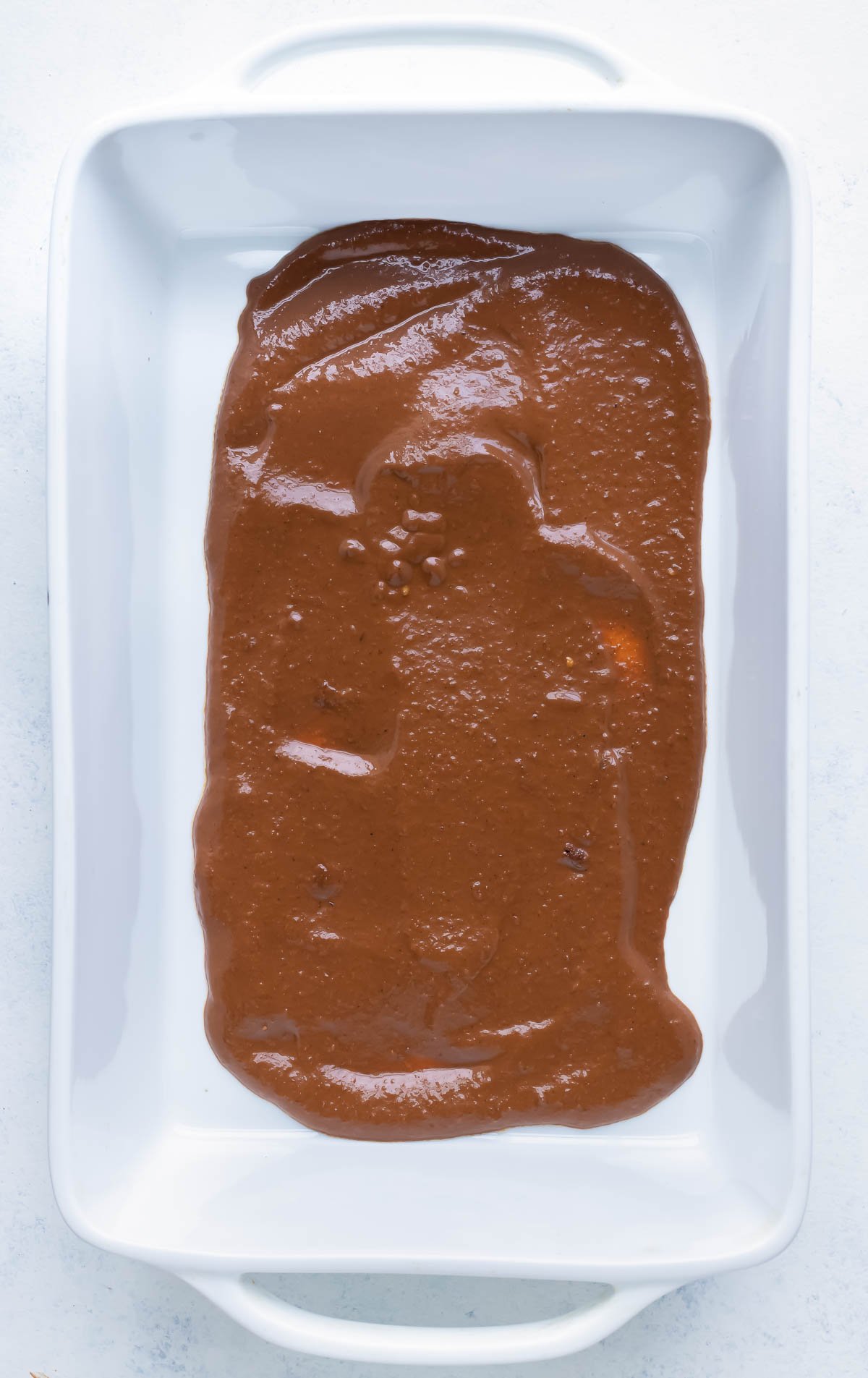 Mole sauce is spread all over the bottom of the pan.