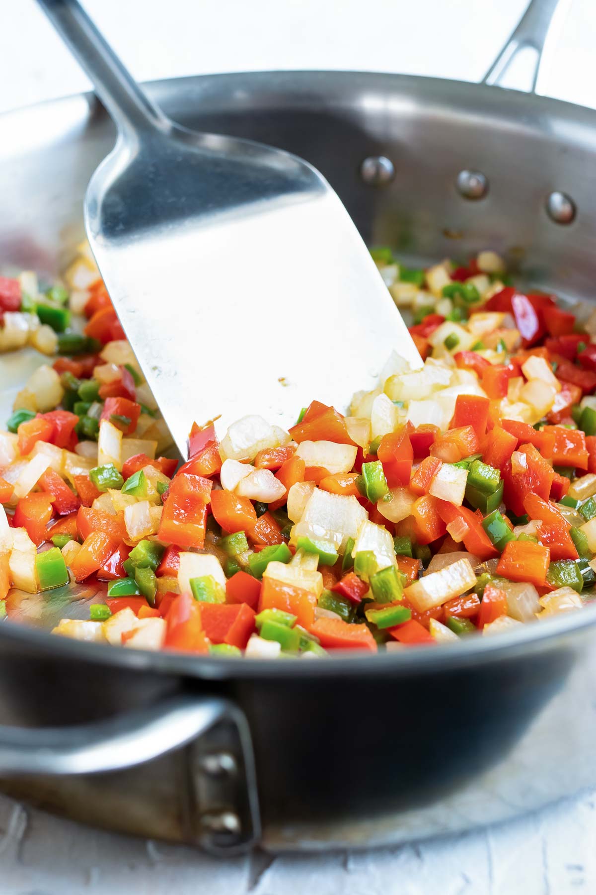 A stainless steel skillet full of jalapeno, onion, and red bell pepper.