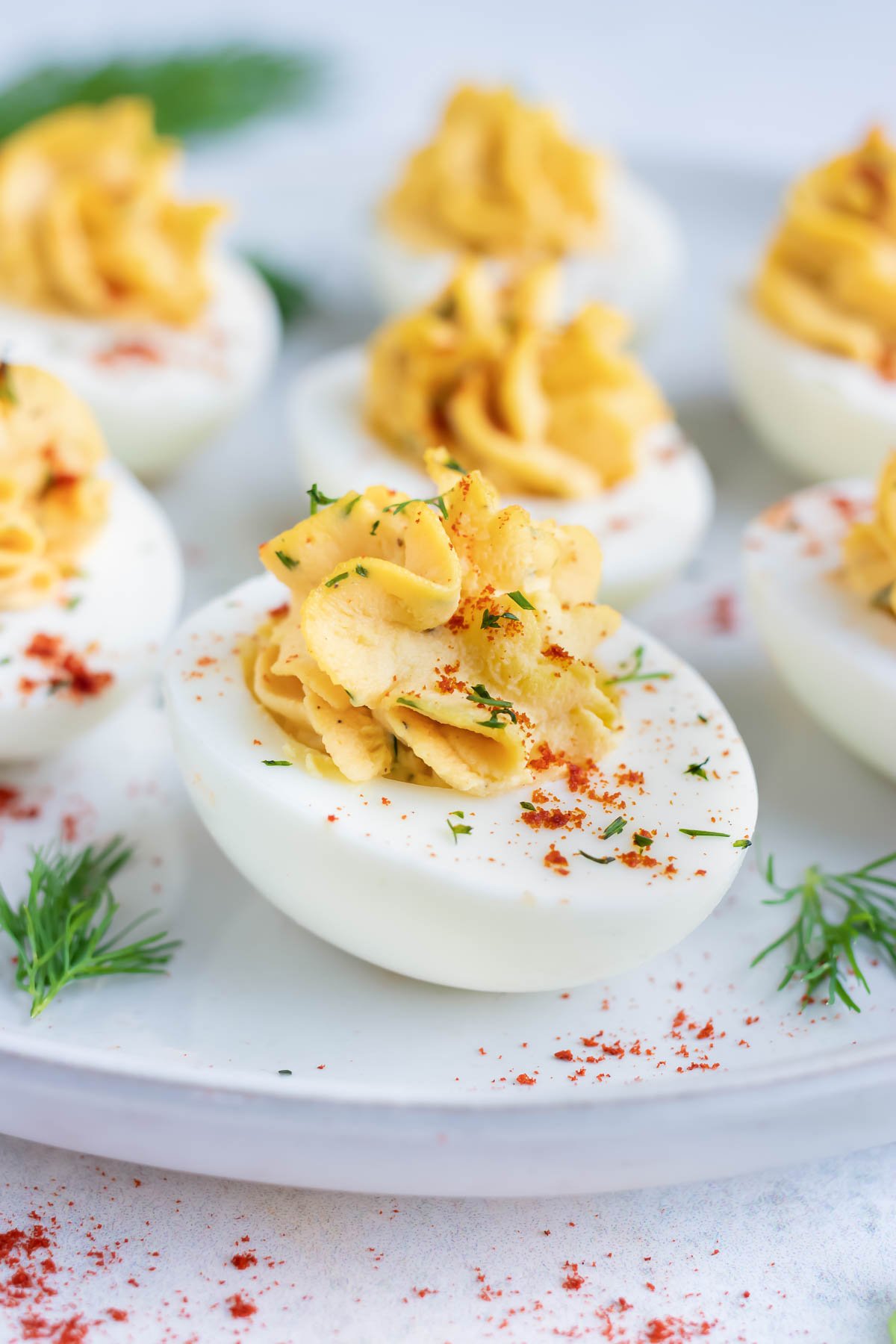 Low carb, keto, and Paleo deviled eggs made with mayonnaise and dill on a white plate.