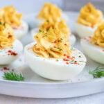 Low carb, keto, and Paleo deviled eggs made with mayonnaise and dill on a white plate.