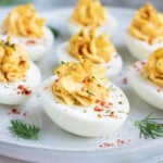 An appetizer platter full of Paleo deviled eggs next to a dozen eggs.