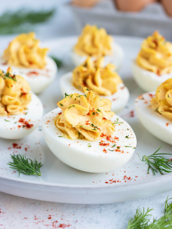 An appetizer platter full of Paleo deviled eggs next to a dozen eggs.