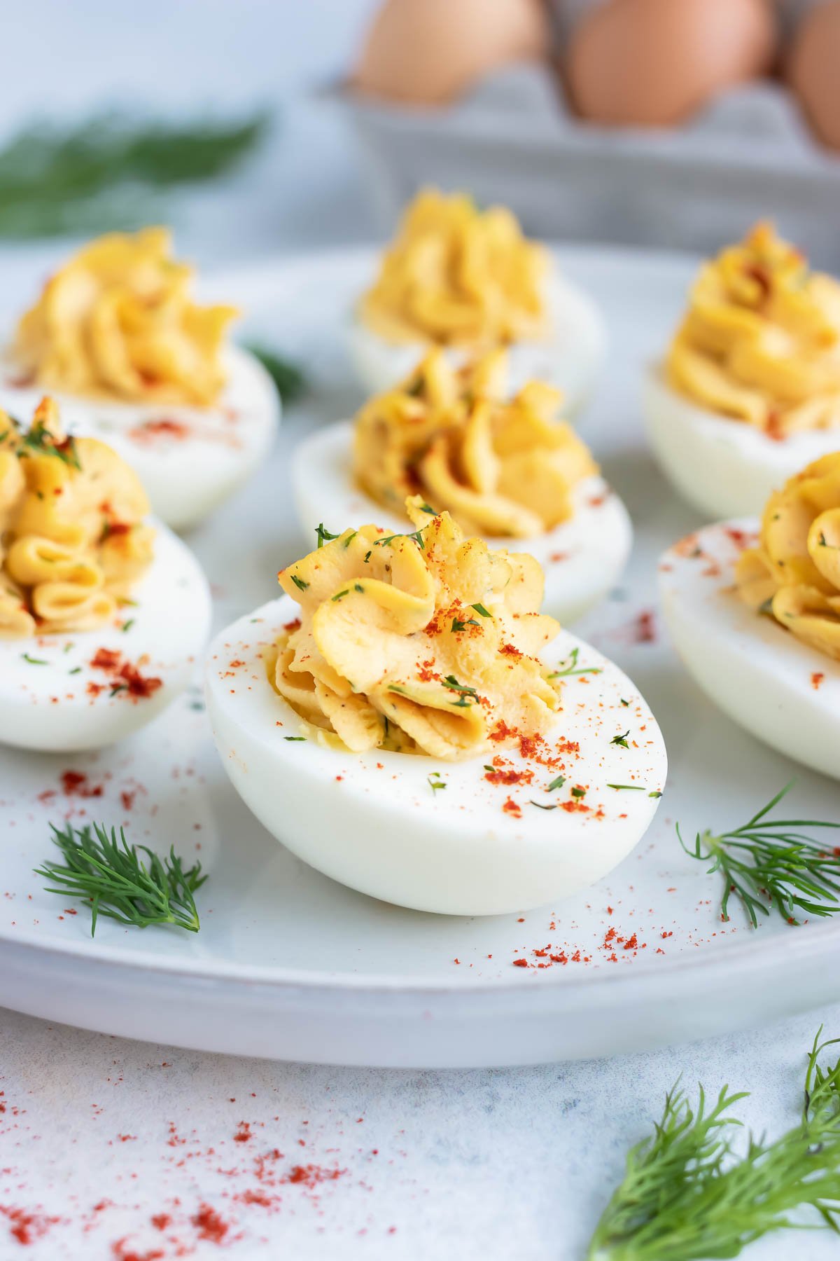 An appetizer platter full of Paleo deviled eggs next to a dozen eggs.