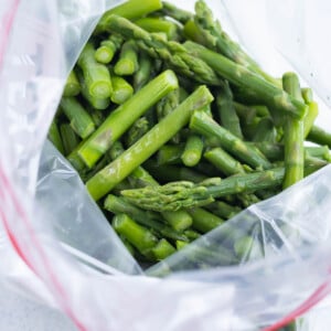 Frozen cut up asparagus in a freezer bag opened at the top.