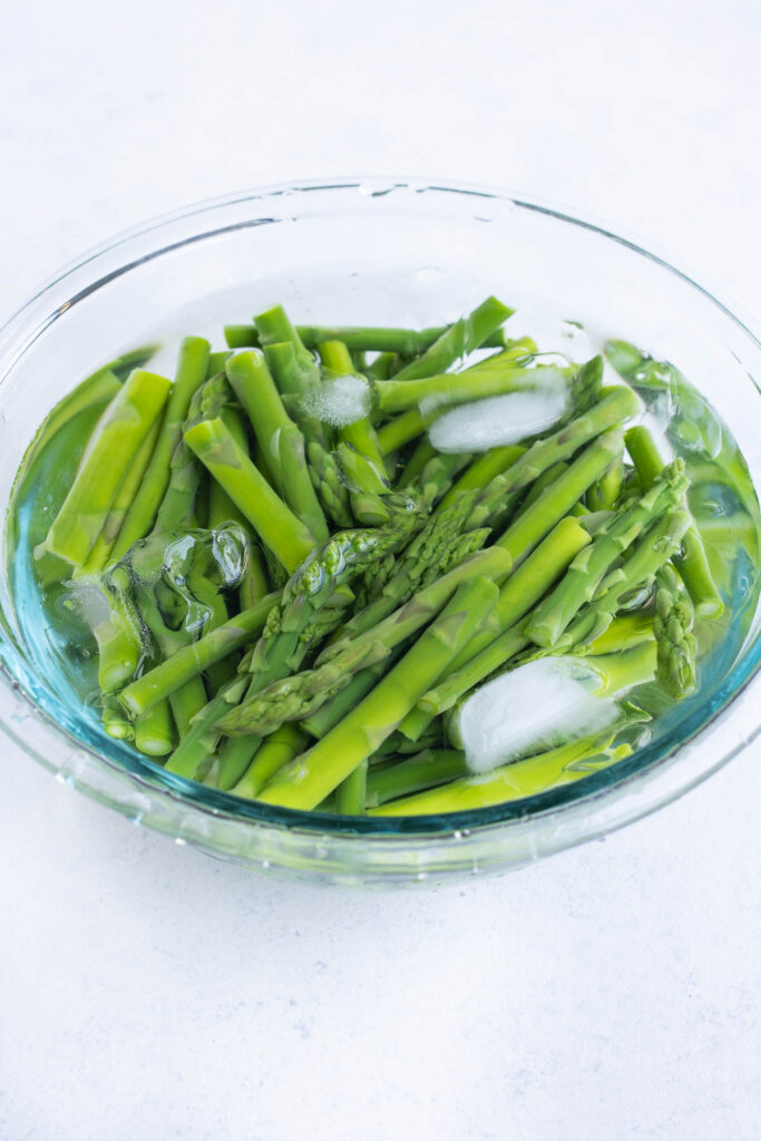 Cut asparagus in a glass bowl full of ice water.