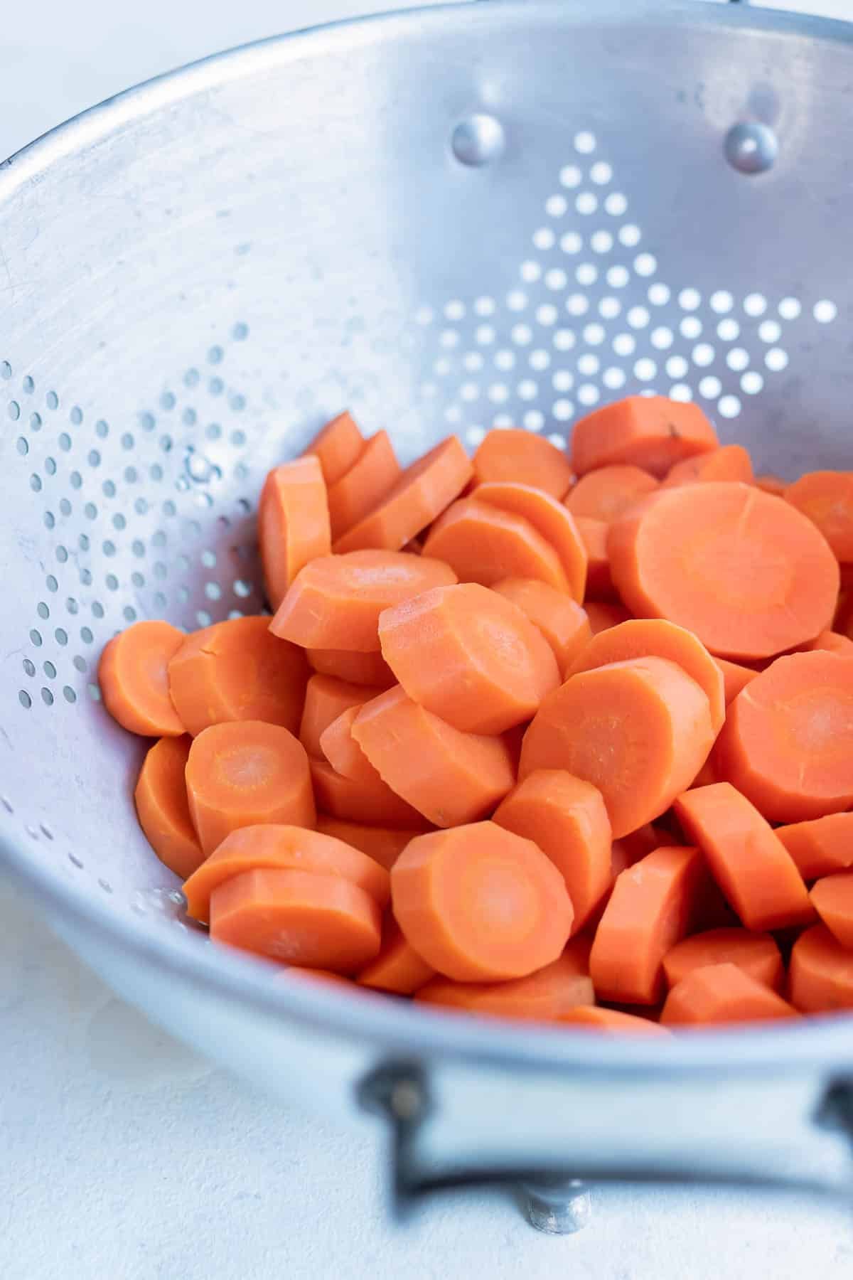Boiled carrots are drained in a colander.