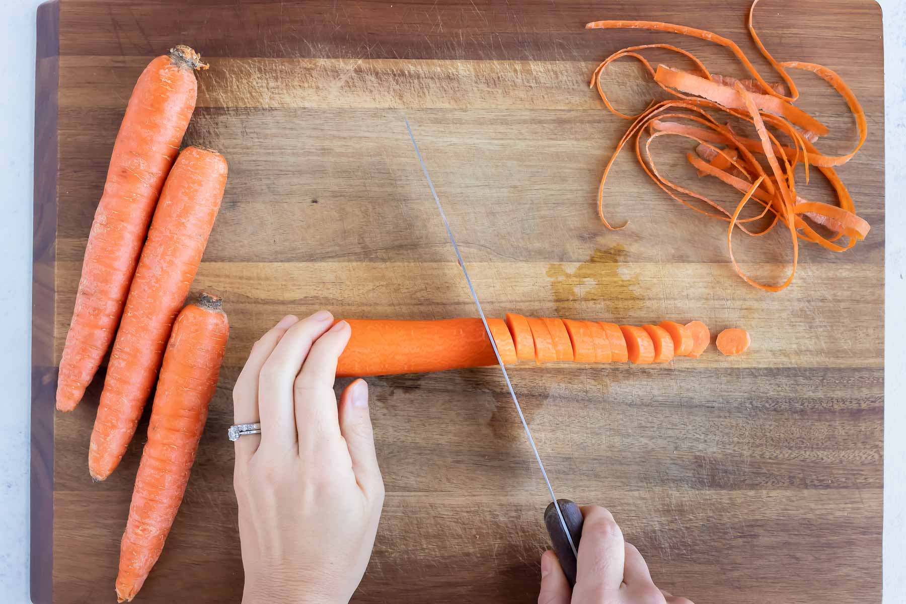 Carrots are sliced on a cutting board before boiling.