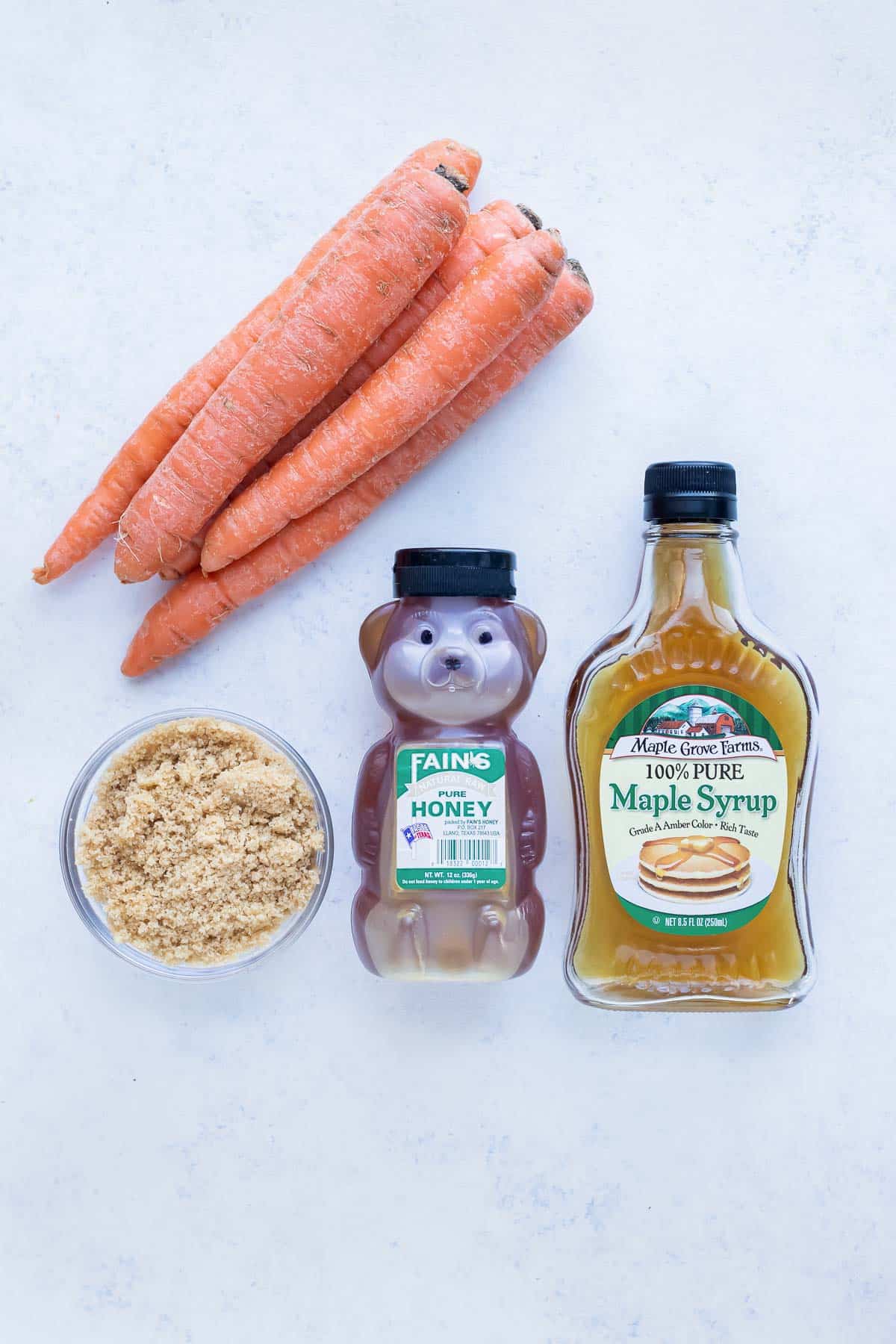 Carrots, honey, brown sugar, and maple syrup are shown for this recipe.