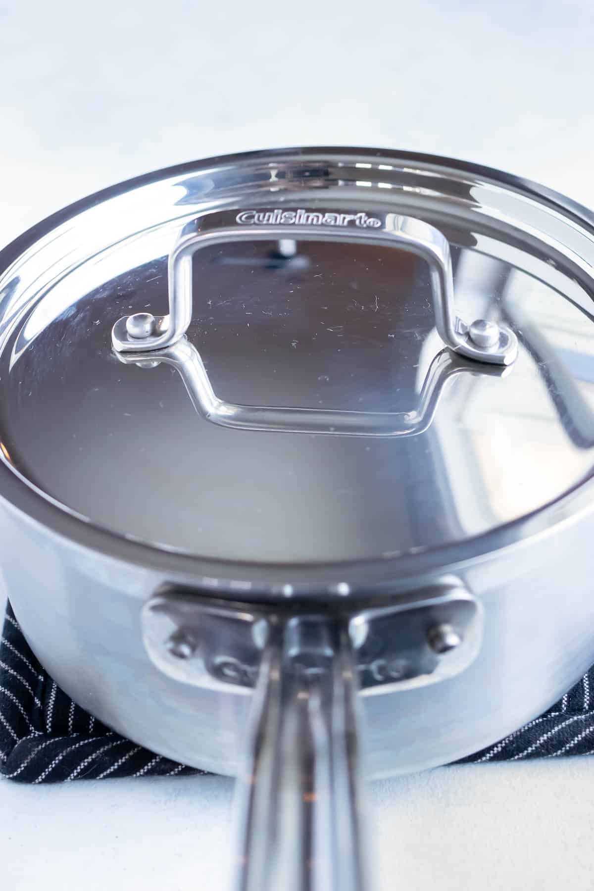 A metal pot is covered with a lid on the stove.