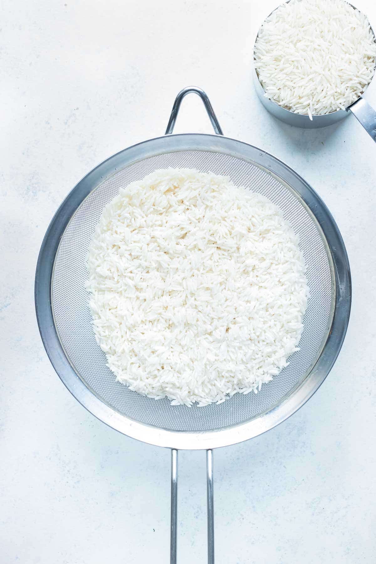 Rice is rinsed in a strainer before cooking in the instant pot.