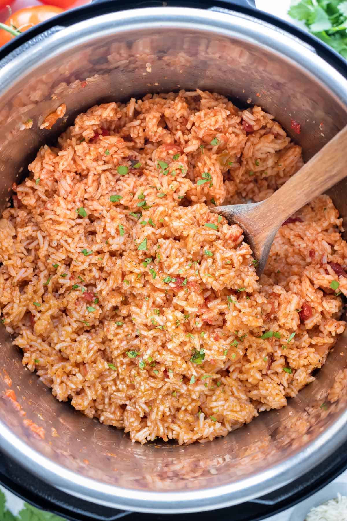 A wooden spoon is used to stir the Mexican rice in the instant pot.