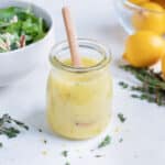Salad dressing is kept in a jar on the counter before being used on salad.