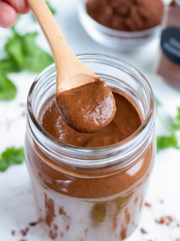 A mason jar full of authentic mole sauce is shown on the counter with a spoon.