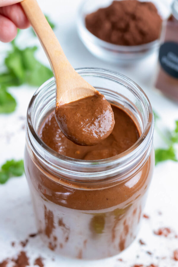 A mason jar full of authentic mole sauce is shown on the counter with a spoon.