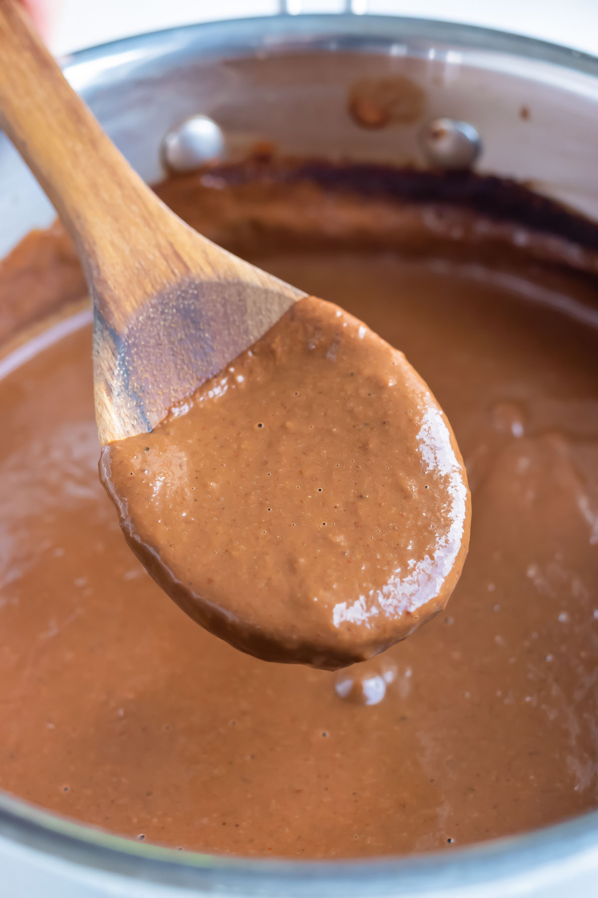 A wooden spoon is used to stir and dish authentic mole sauce.