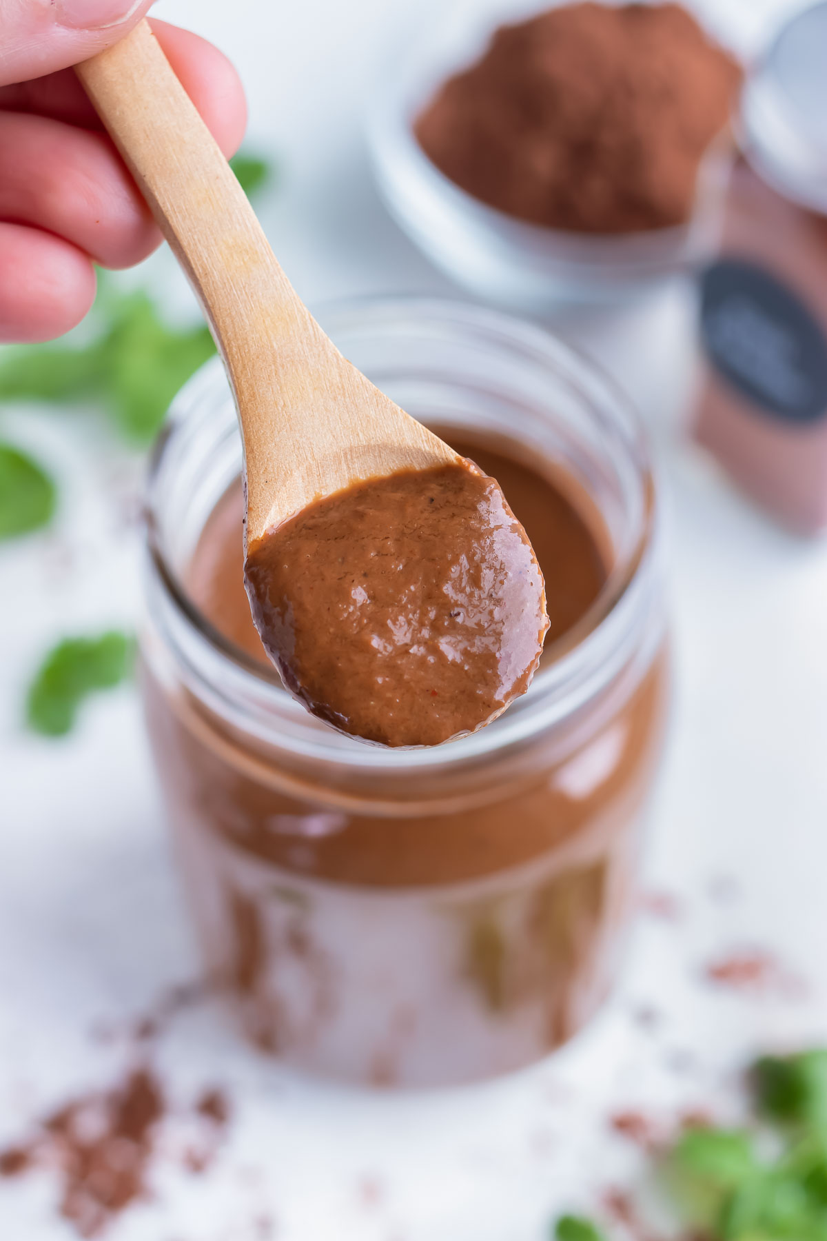 A big scoop of mole sauce is served from a jar.