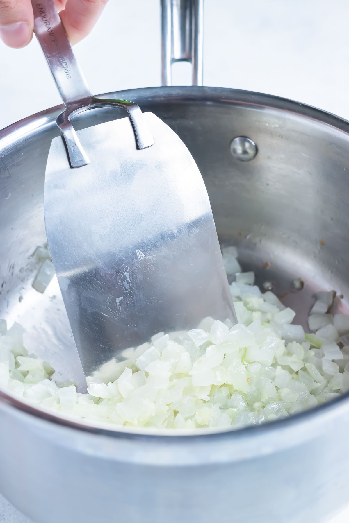 Onions are cooked in a saucepan as the first step in a mole sauce recipe.