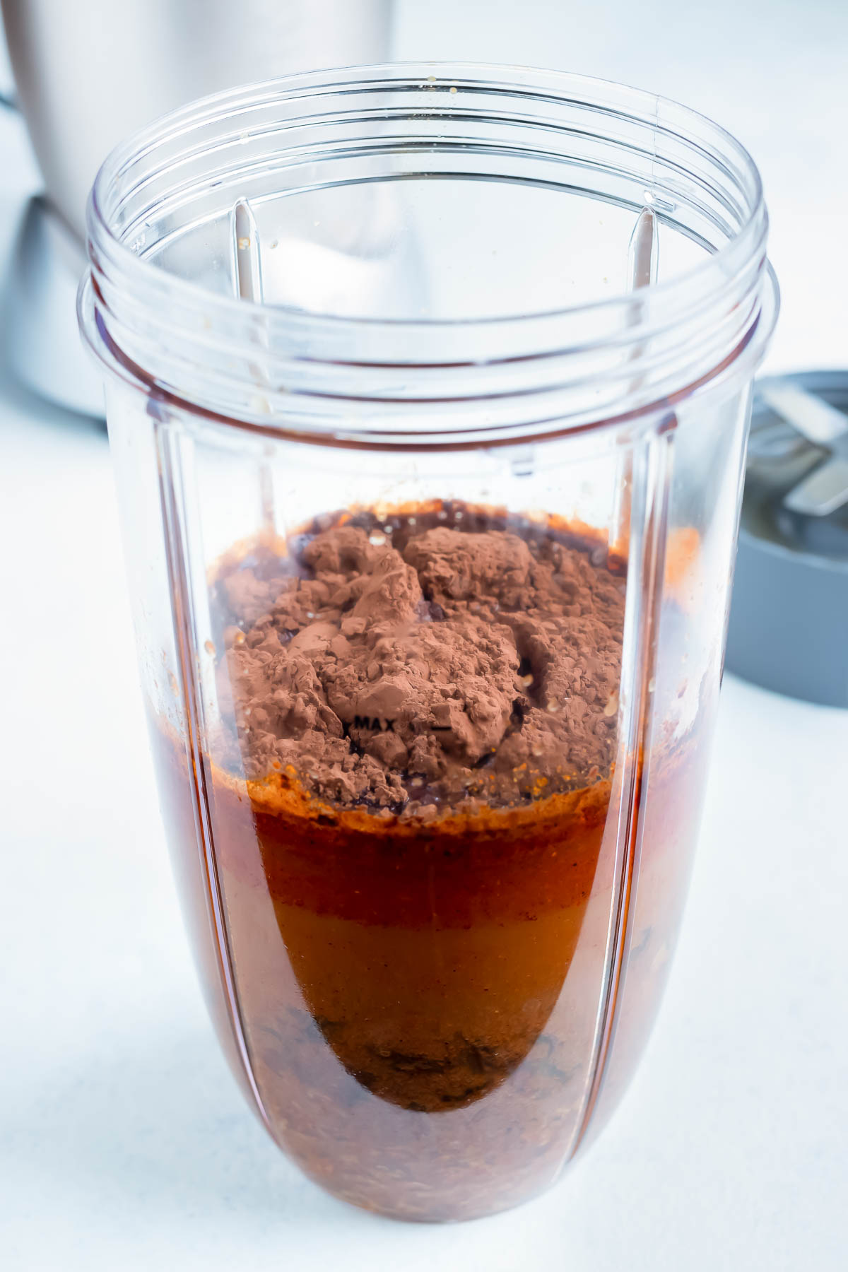 The onions, chipotle peppers, almond butter, raisins, cocoa powder, and remaining broth are added to a high speed blender.