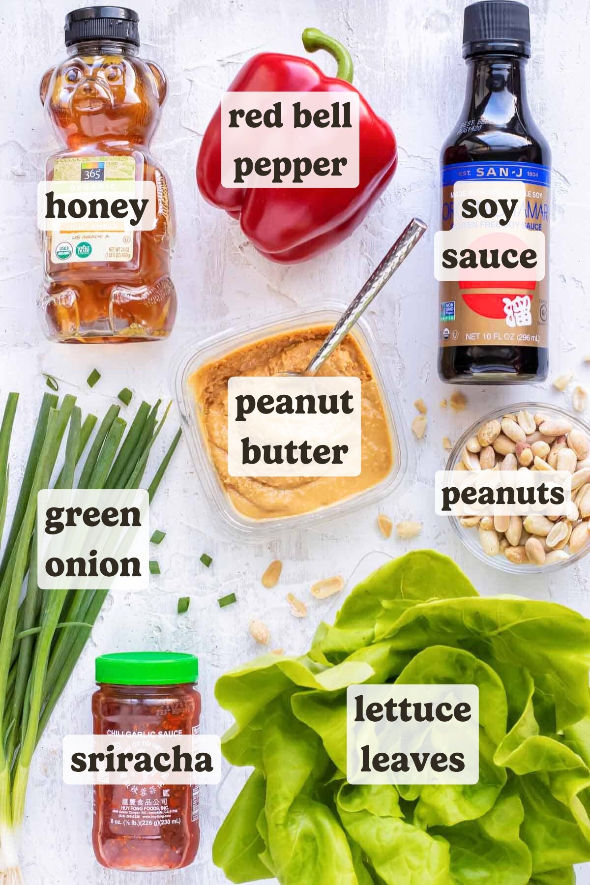 Honey, red bell pepper, soy sauce, peanut butter, sriracha, green onions, and lettuce leaves for a shredded chicken lettuce wraps recipe.