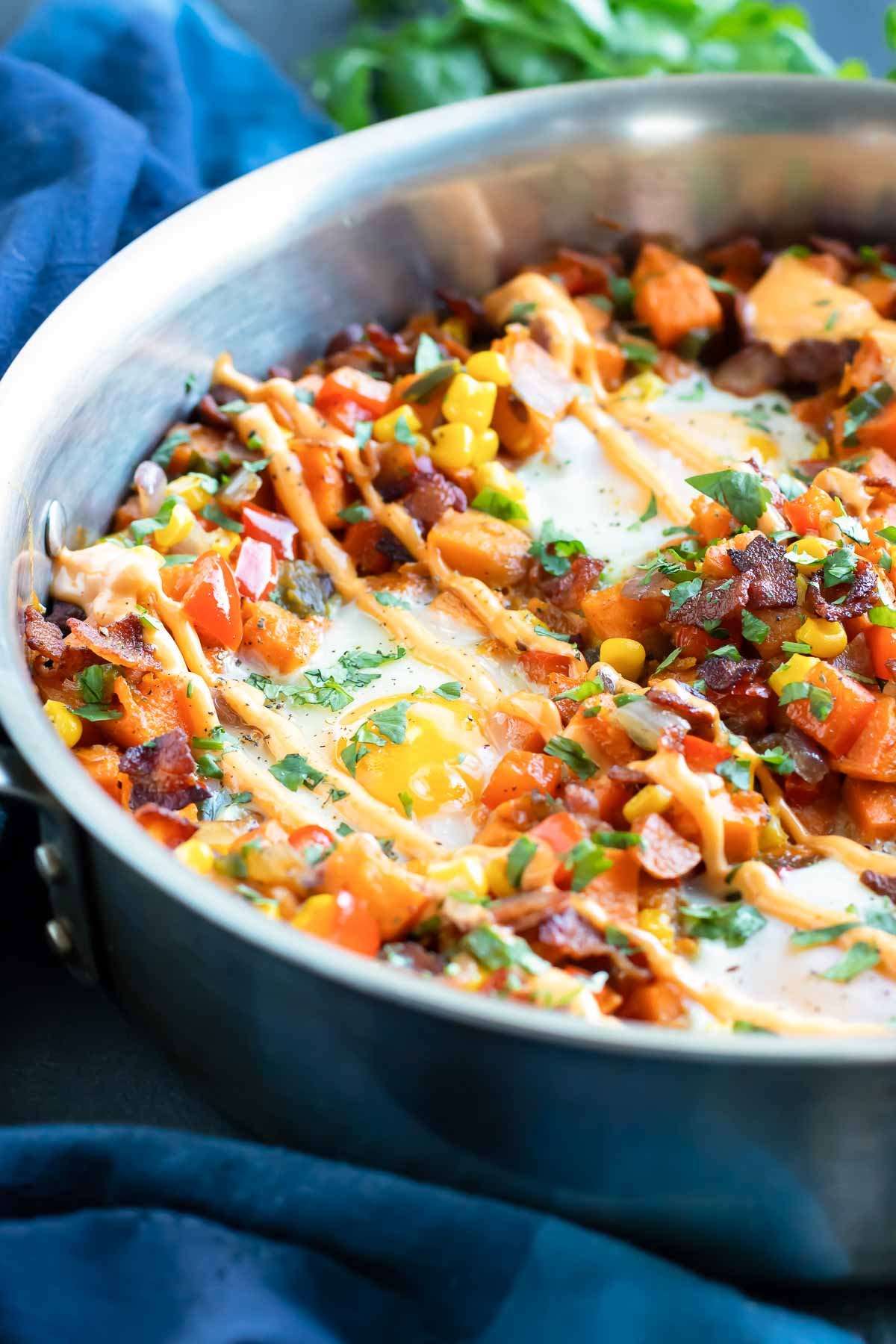 An overhead shot of sweet potato hash with sriracha mayo drizzled on top.