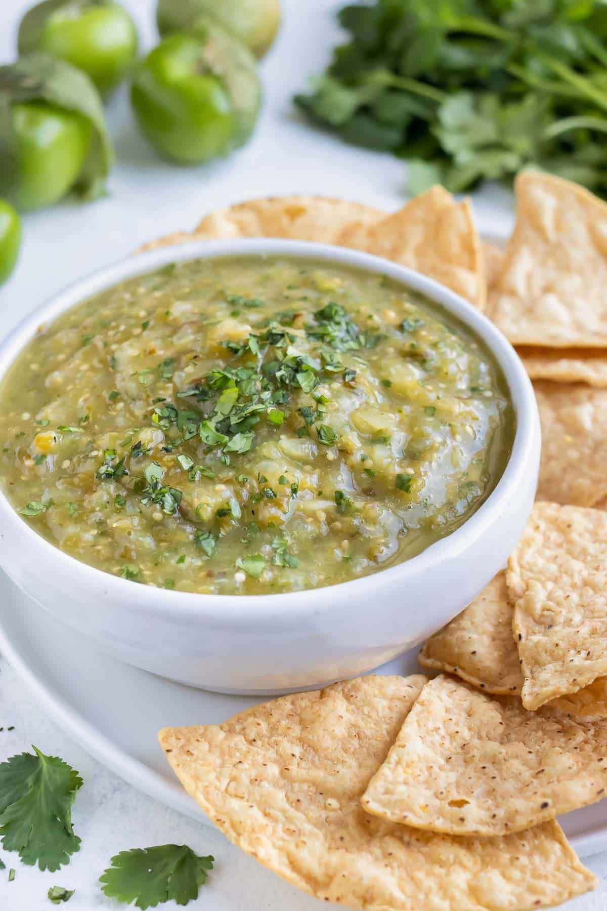 A bowl of healthy salsa verde is served with chips for an appetizer.