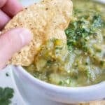 A chip is dipped into a big bowl of homemade salsa verde.