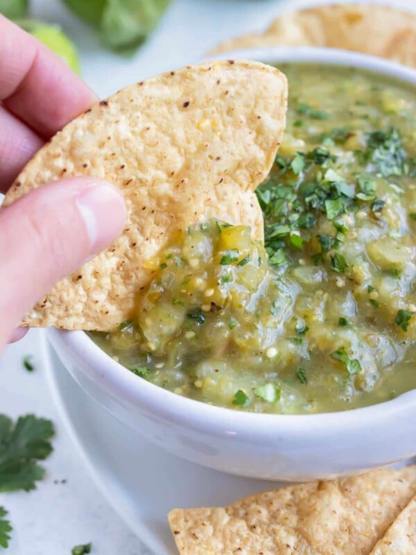 A chip is dipped into a big bowl of homemade salsa verde.