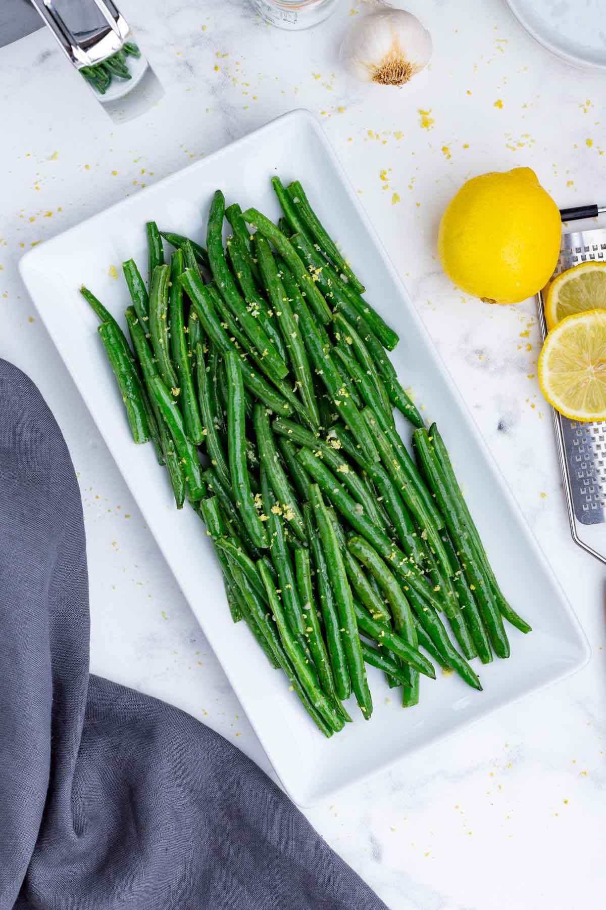 Green beans are served on a white plate after cooking in the air fryer.